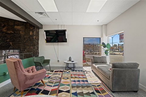 A living room with a stone wall and a flat screen TV mounted on the wall.