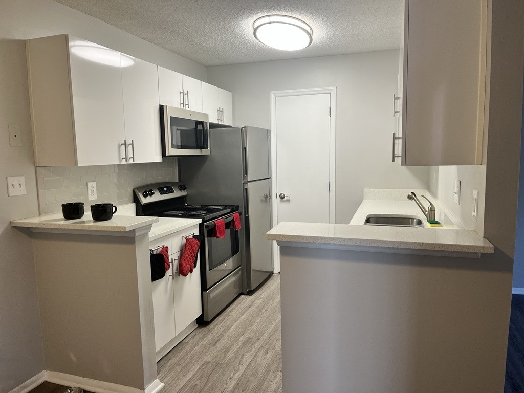 an empty kitchen with stainless steel appliances and white cabinets