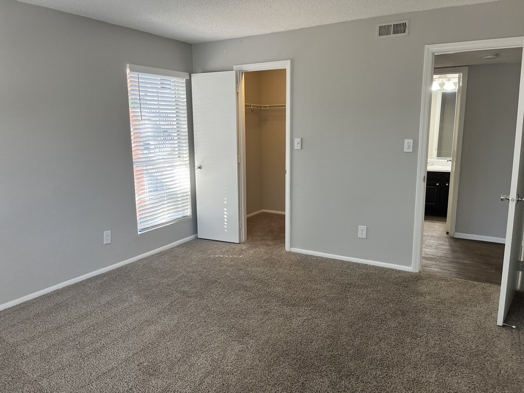 a bedroom with a carpeted floor and a door to a closet