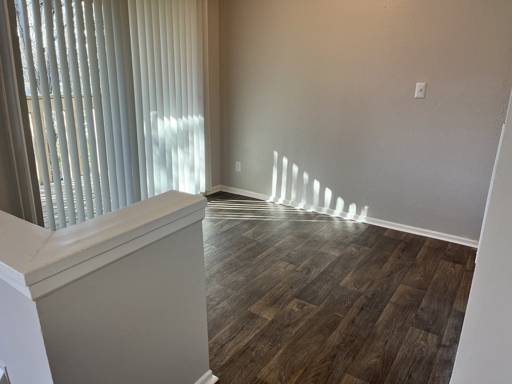 an empty living room with wood flooring and a large window