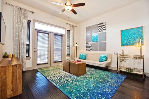 A living room with a white couch and a blue rug.