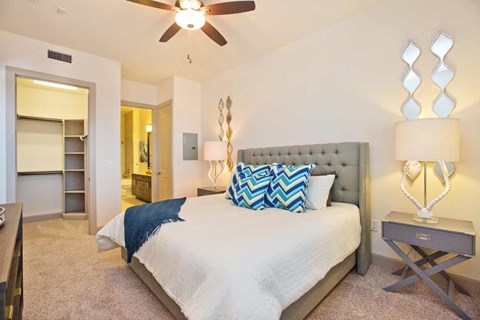 A bedroom with a bed, a nightstand, and a ceiling fan.