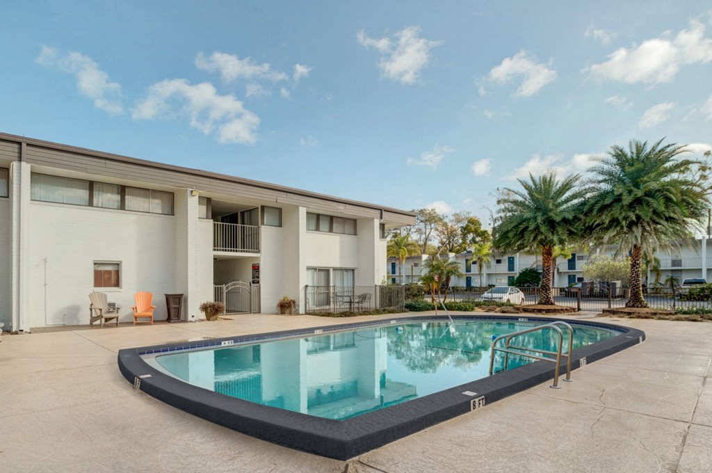 a swimming pool in front of a building with palm trees