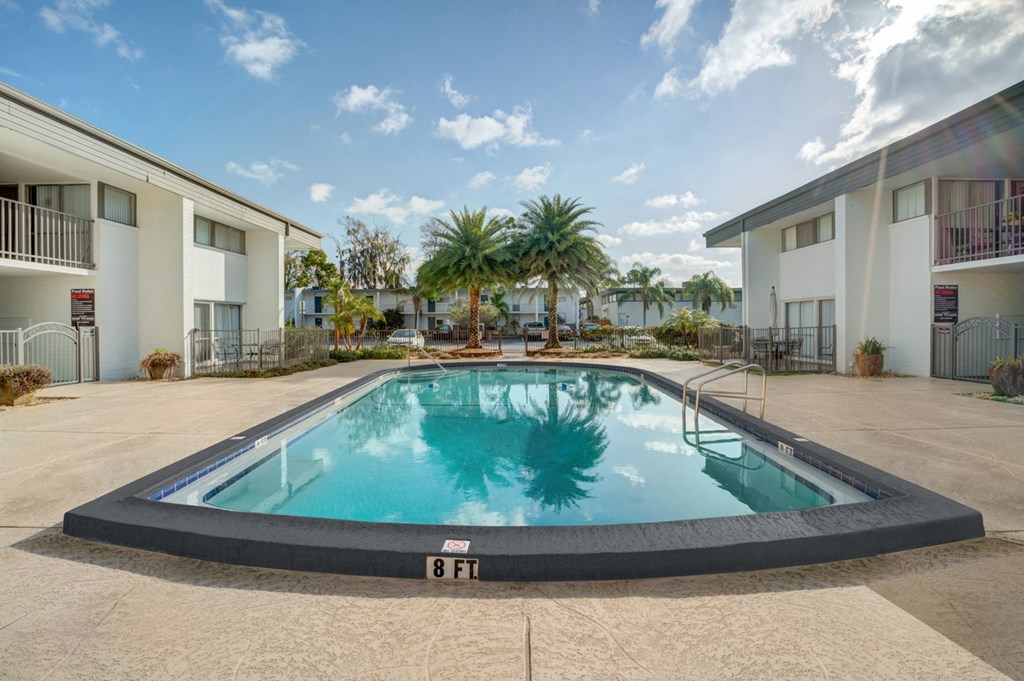 a pool in the middle of two apartment buildings with palm trees