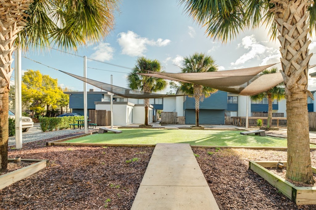 a courtyard with grass and hammocks and a building in the background