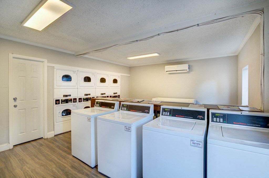 a laundry room with four washers and dryers and a door to a closet