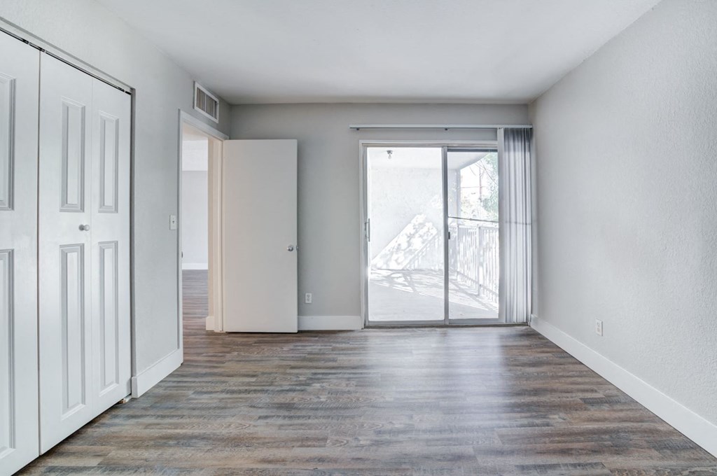 an empty living room with a door to a balcony