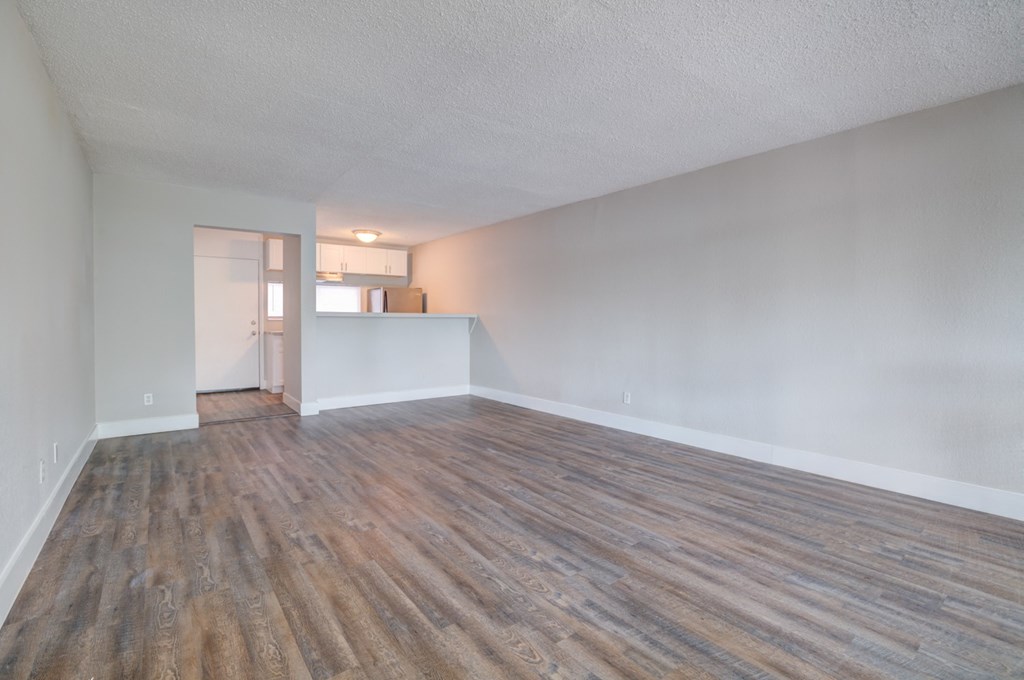 an empty living room with wood flooring and white walls