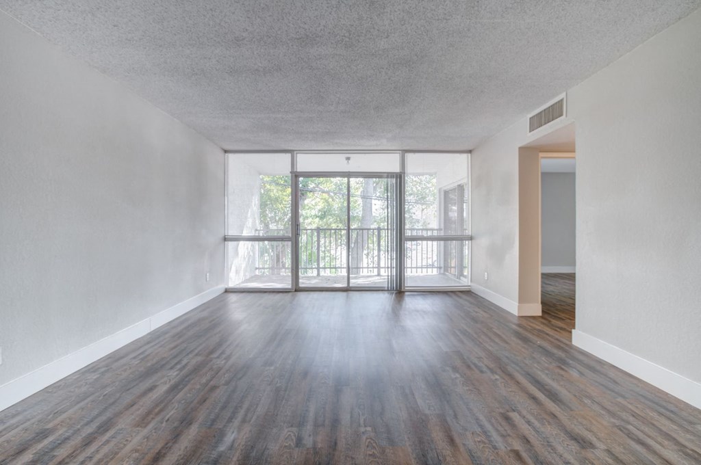 an empty living room with wood flooring and a balcony