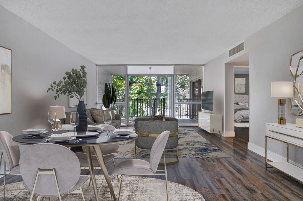 a living room with a dining room table and chairs and a balcony