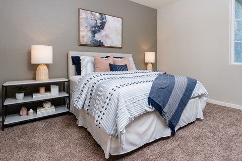 A bedroom with a large bed and a nightstand with a lamp.