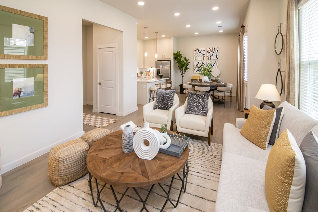 A living room with a white couch, a coffee table, and a dining table in the background.