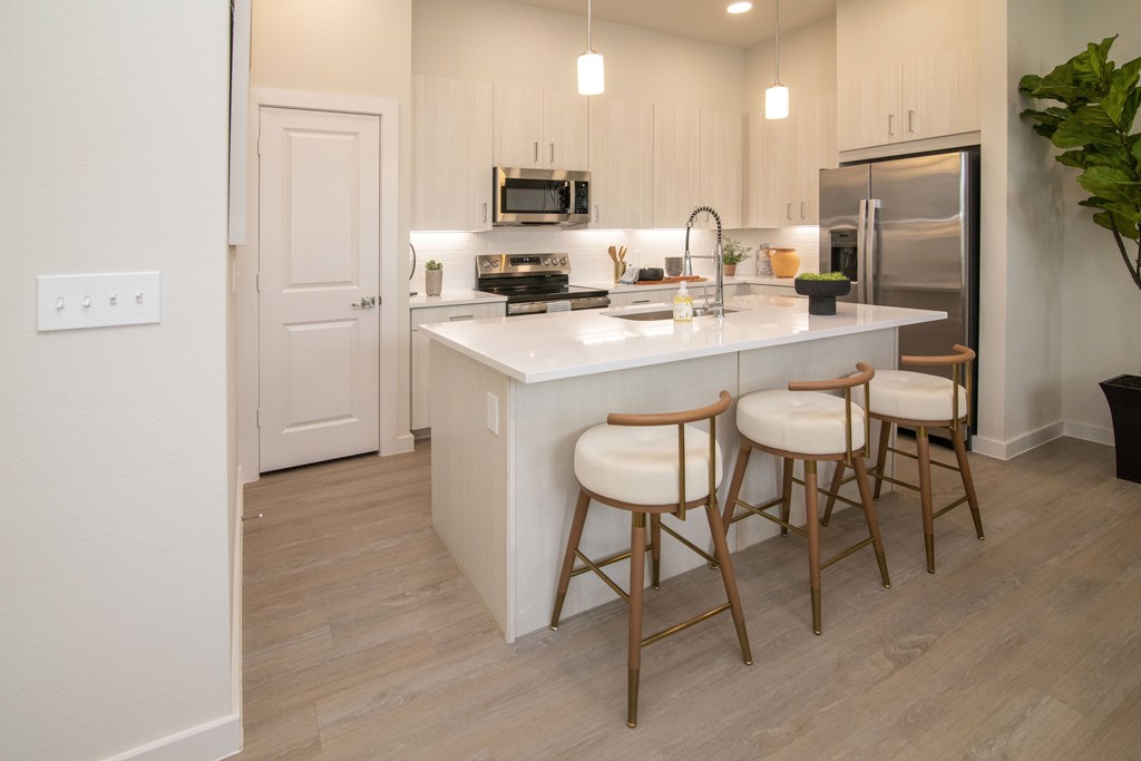 A kitchen with a white countertop and wooden chairs.