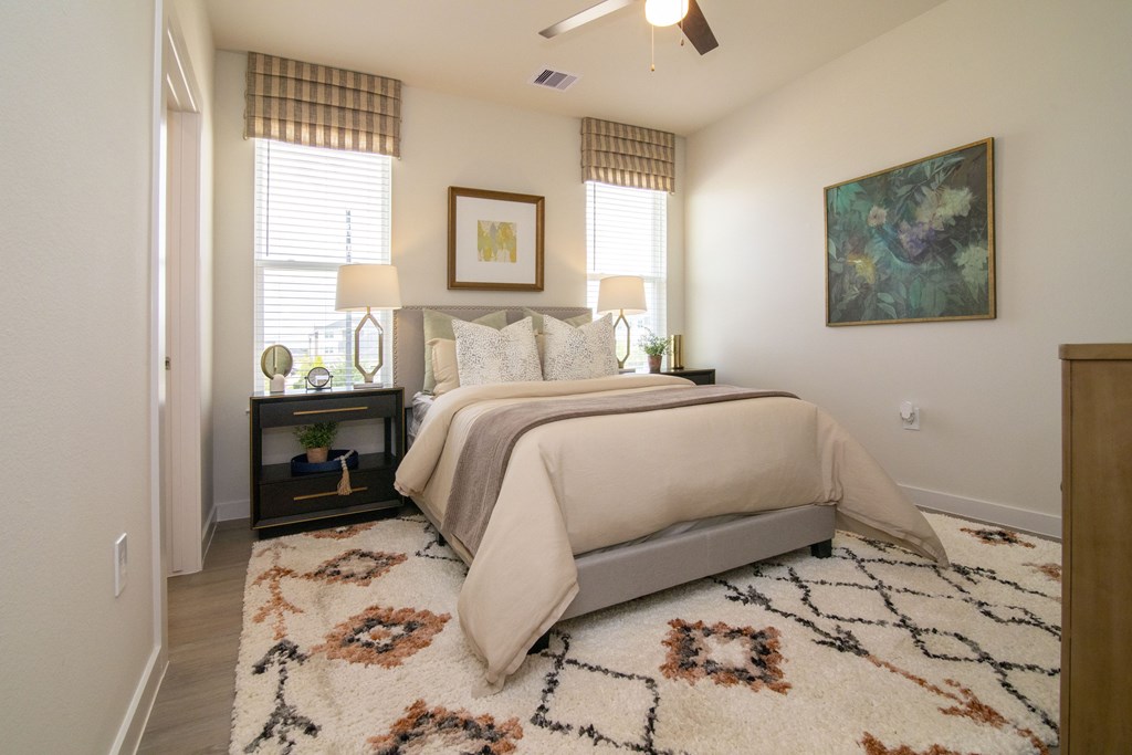 A bedroom with a large bed and a rug on the floor.