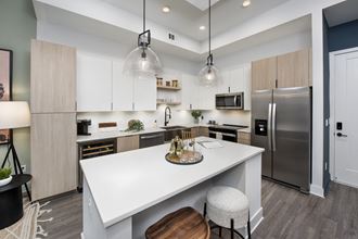 an open kitchen with a large white island and stainless steel appliances