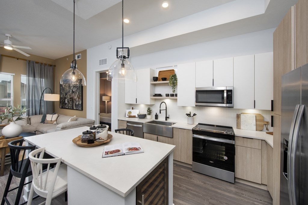 an open kitchen and living room with a large white island and a dining table
