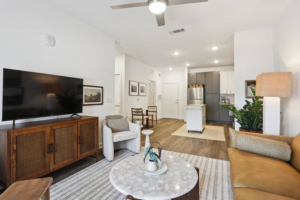 a living room with a tv and a kitchen in the background