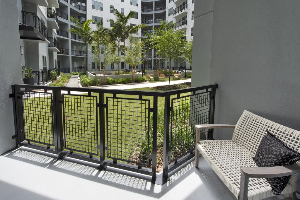 a balcony with a couch and a chair overlooking a courtyard