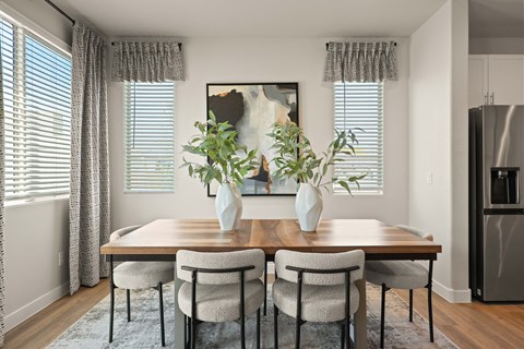 a dining room with a wooden table and chairs and two vases with plants