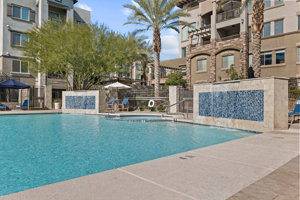 A swimming pool surrounded by a stone wall and palm trees.