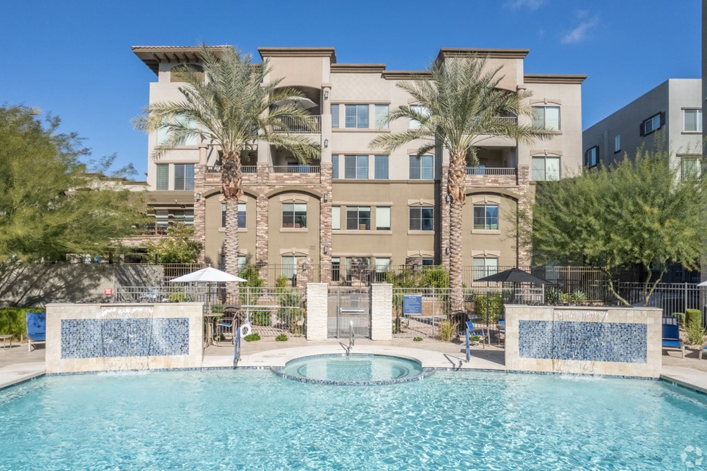a swimming pool with a fountain in front of an apartment building