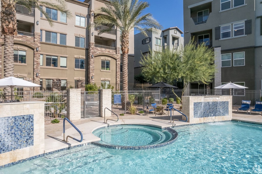 a swimming pool with a jacuzzi in front of an apartment building