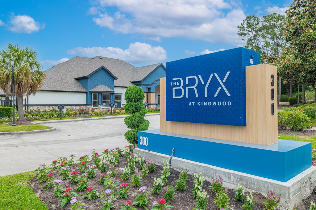 A blue and wooden sign for The Bryx at Kingwood stands in front of a house.