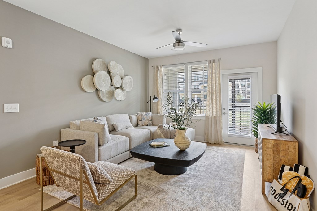 A living room with a sofa, chair, and a table with a vase on it.