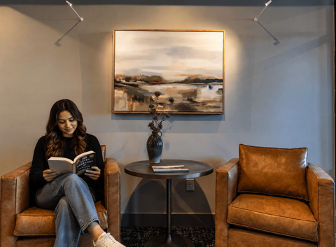 A woman is sitting in a chair reading a book.