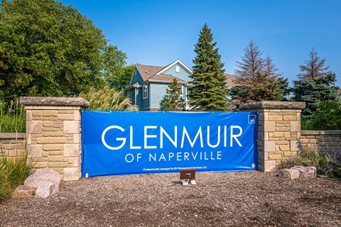 A blue sign that says Glenmuir of Naperville in front of a house.