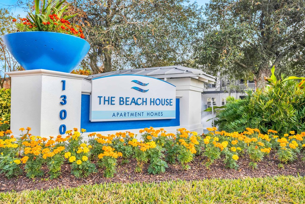 a sign for the beach house apartments in aptos with flowers