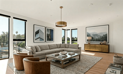 A modern living room with a large grey sofa, a coffee table, and a view of the city.