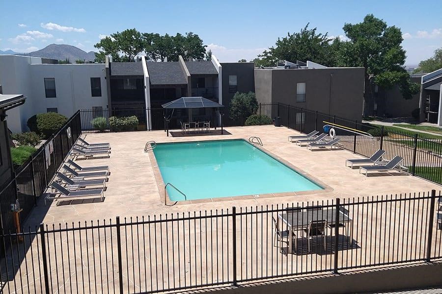 a pool with a fence around it and a building in the background