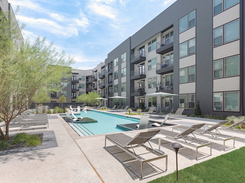 an outdoor pool with lounge chairs and umbrellas at the central apartments near uptown and