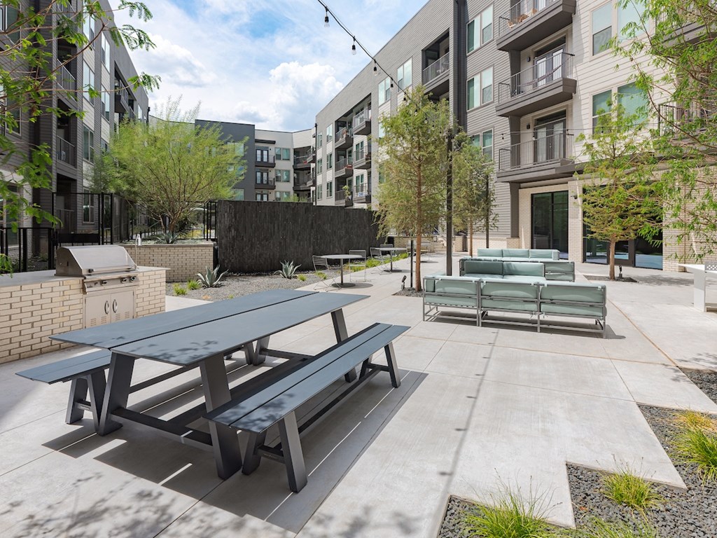 a courtyard with picnic tables and fire pits at the central apartments near uptown and downtown min