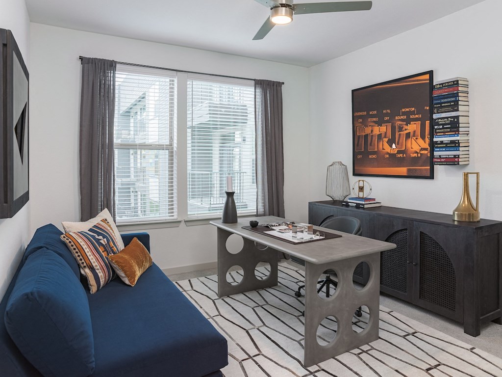 a living room with a blue couch and a gray coffee table in front of a large window