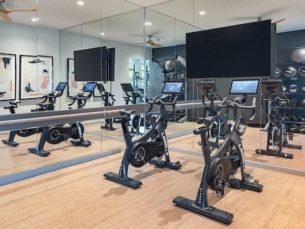 a room filled with lots of cardio machines and flat screen televisions