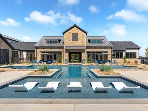 a large swimming pool in front of a house with lounge chairs