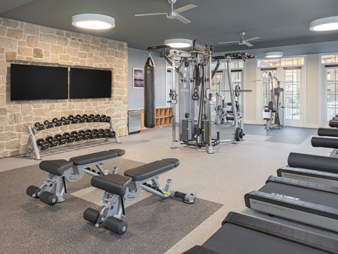 a gym with weights and a tv and a stone wall