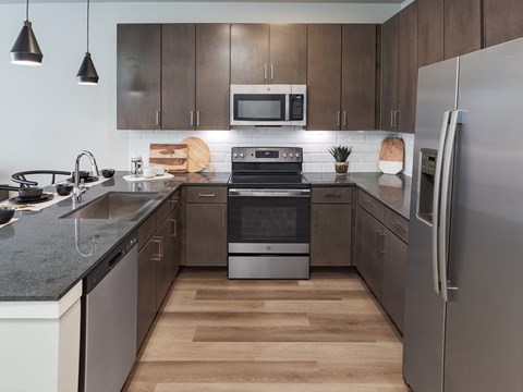 A modern kitchen with a stainless steel refrigerator and wooden floors.