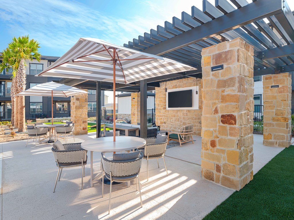 A patio with a table and chairs under a pergola.