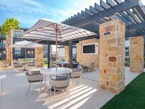 A patio with a table and chairs under a pergola.