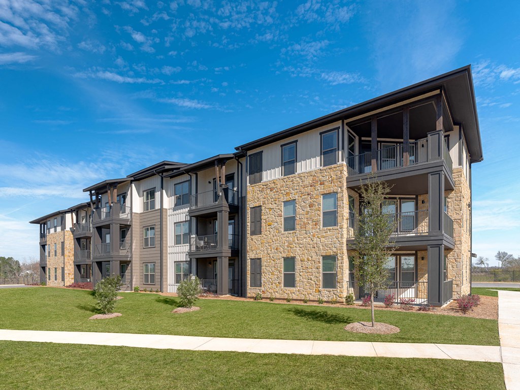 A modern apartment building with a stone facade and balconies.