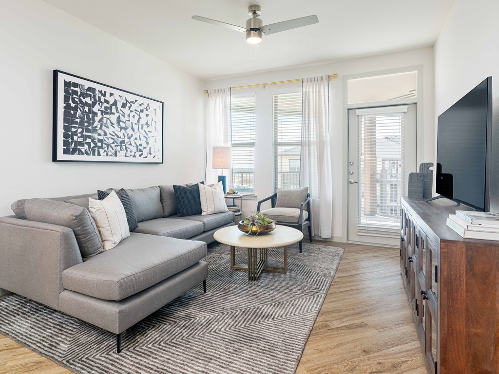 A living room with a grey couch, a coffee table, and a painting on the wall.