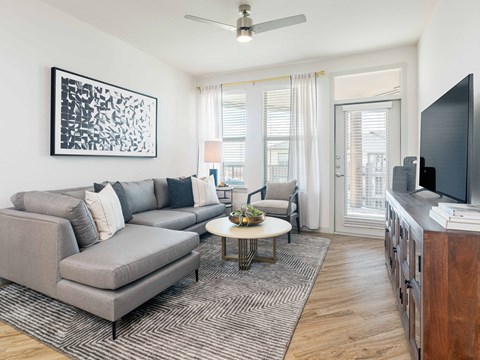 A living room with a grey couch, a coffee table, and a painting on the wall.