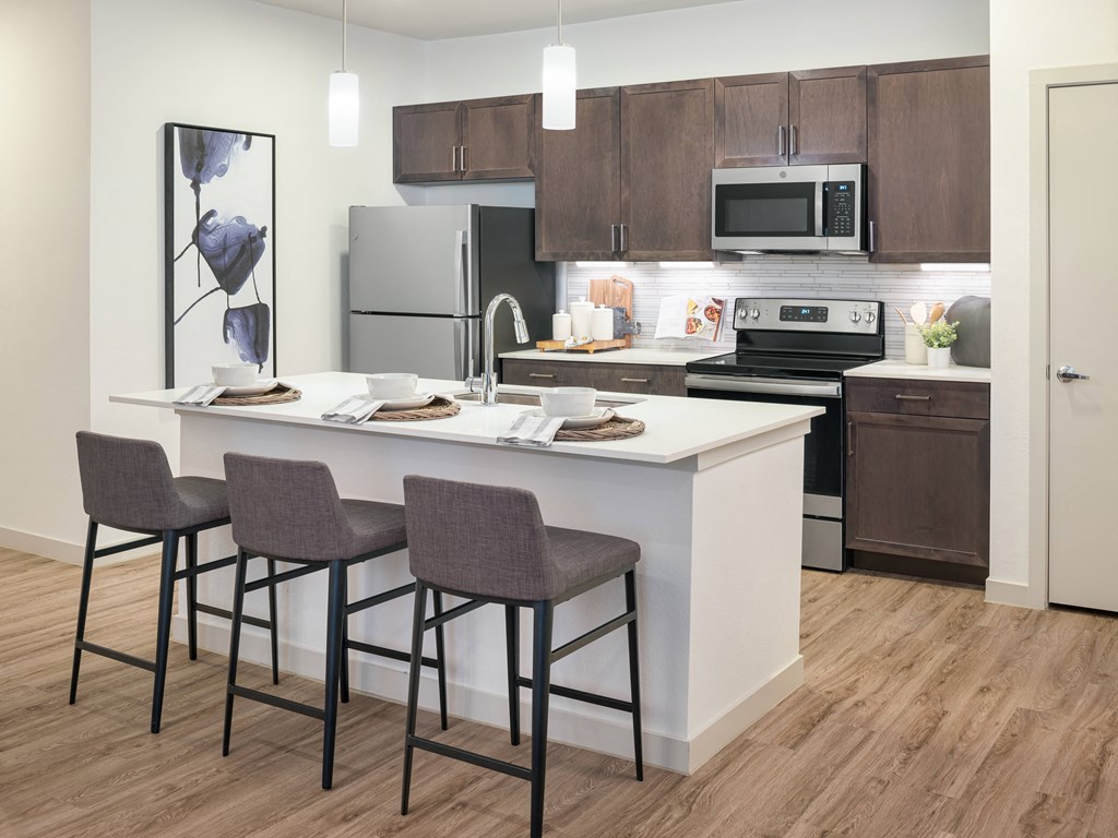 A kitchen with a white island and brown cabinets.
