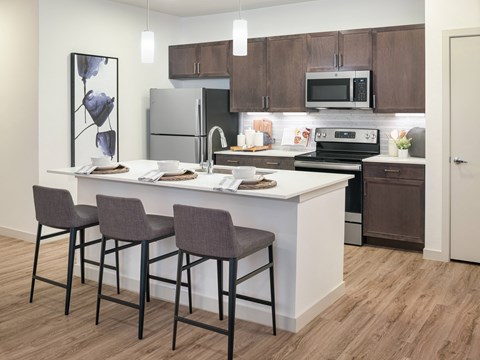 A kitchen with a white island and brown cabinets.