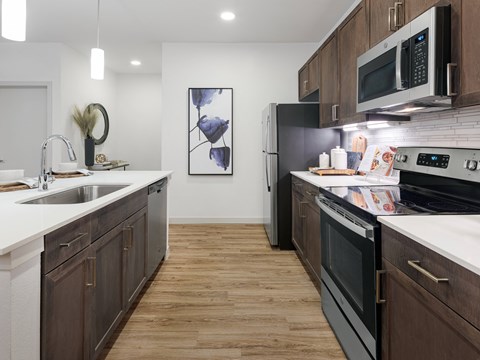 A modern kitchen with dark wood cabinets and stainless steel appliances.