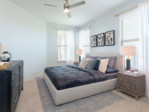 A bedroom with a bed, nightstands, and a ceiling fan.