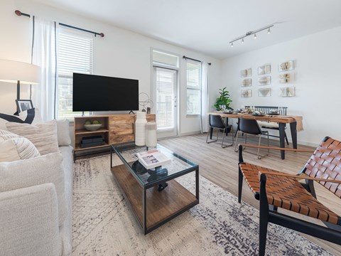A living room with a white couch, a wooden coffee table, and a flat screen TV.